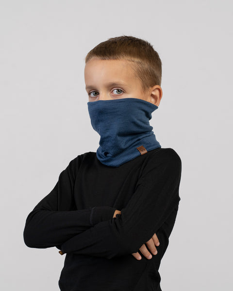 Boy with arms crossed wearing a blue Merino wool neck gaiter – versatile thermal accessory for cold weather.