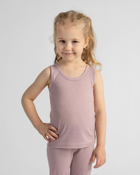 Three-quarter portrait of a smiling young girl posing with her hand on her hip in a dusty rose sleeveless tank top.