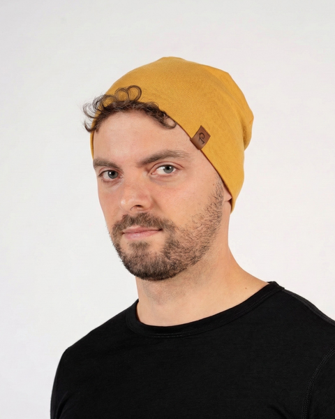 Man wearing yellow merino wool liner beanie, lightweight breathable wool hat designed for everyday comfort and outdoor use.