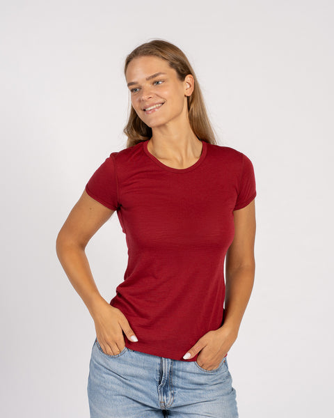 Woman wearing a merino wool menique royal cherry t-shirt and denim jeans standing in white background.
