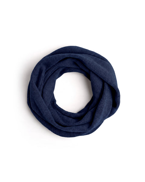A blue knit infinity scarf coiled into a neat circle on a white surface.