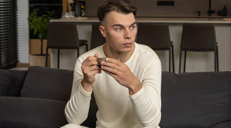 A man relaxing at home in stylish men's merino wool clothing while holding a cup