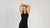 a woman with her hands above her head, smiling, wearing a black merino wool tank top.