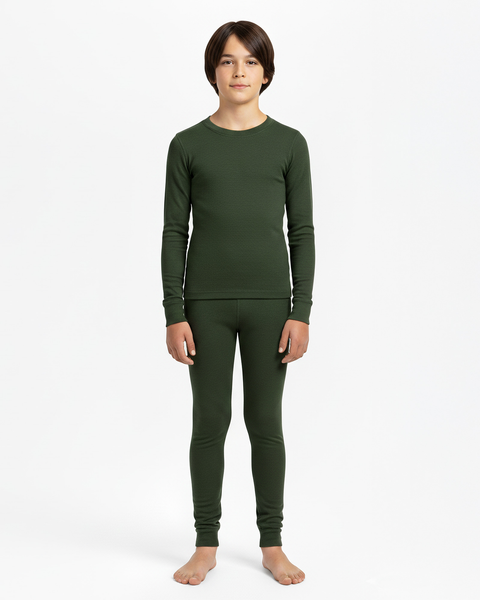 A boy wearing a dark green long-sleeve Merino wool base layer top and matching leggings, standing barefoot against a white studio background.