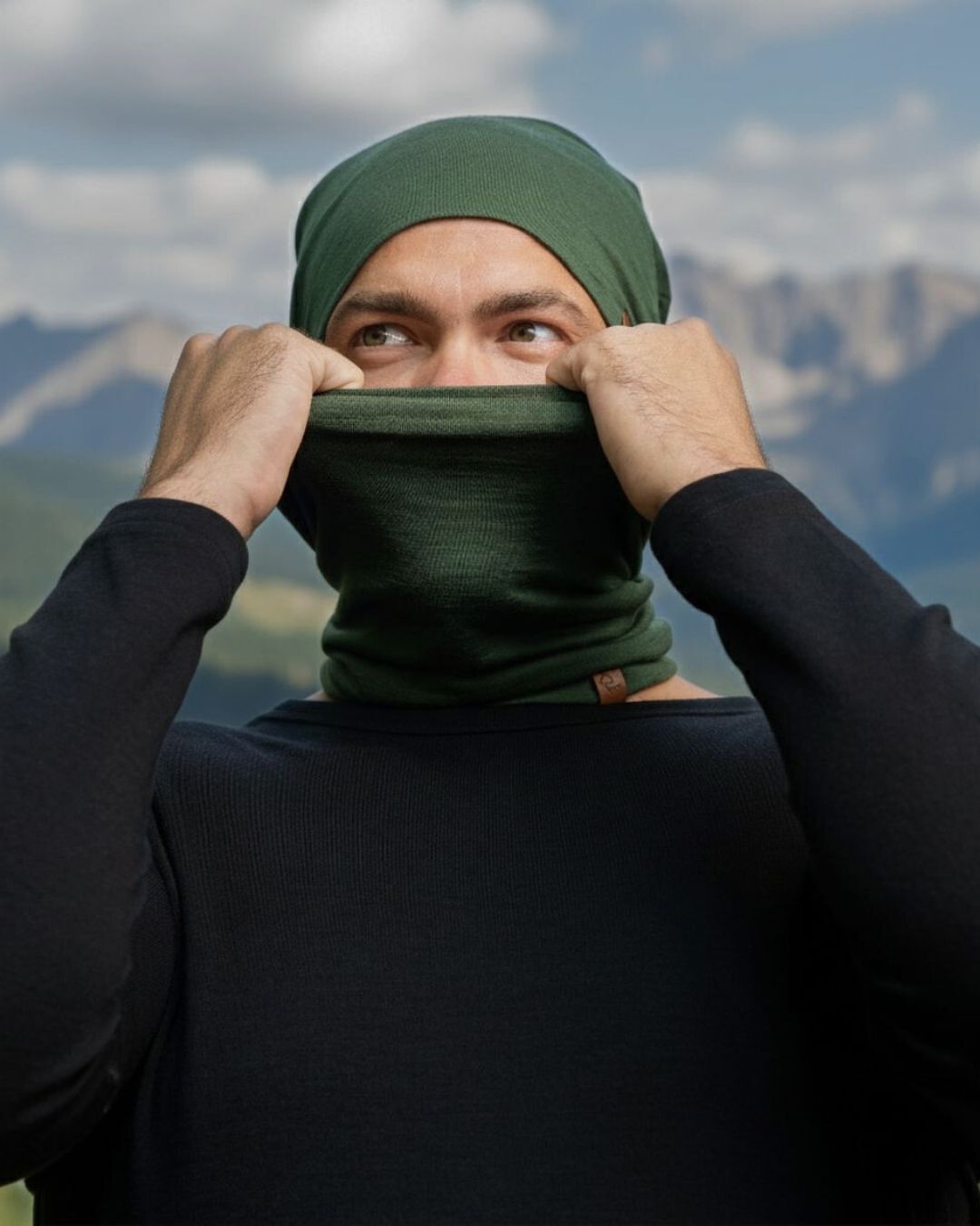 Person wearing a green headscarf and balaclava with mountains in the background