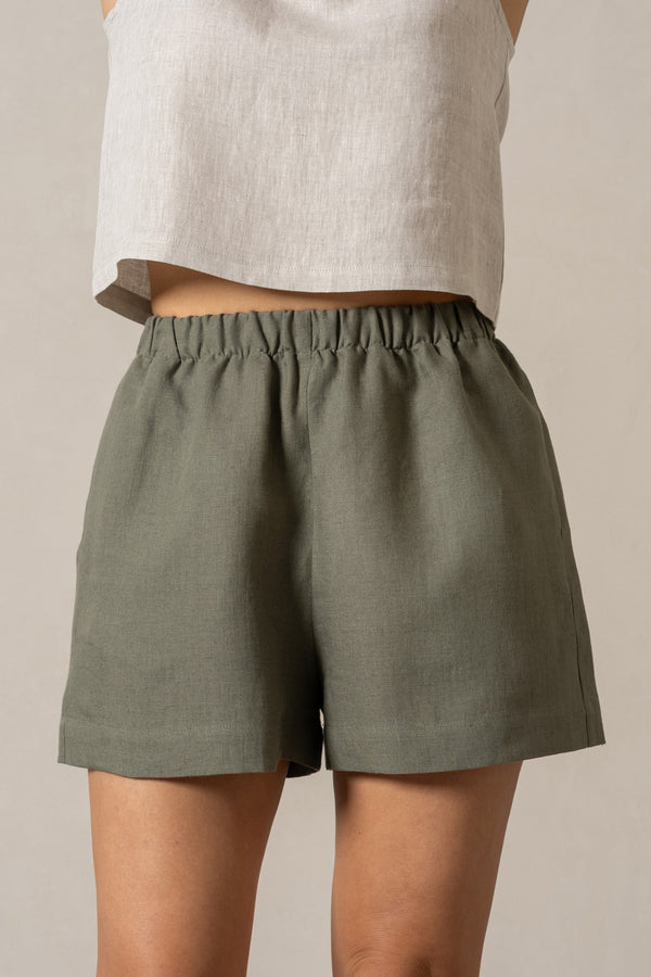 Linen pull-on shorts in the color stone green. High-waisted casual shorts with pockets and elastic waistband. 