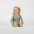 Laughing child lying on the floor in beige bamboo long-sleeve top and bottoms.