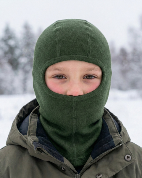 Child wearing dark green merino wool balaclava outdoors in snowy winter landscape