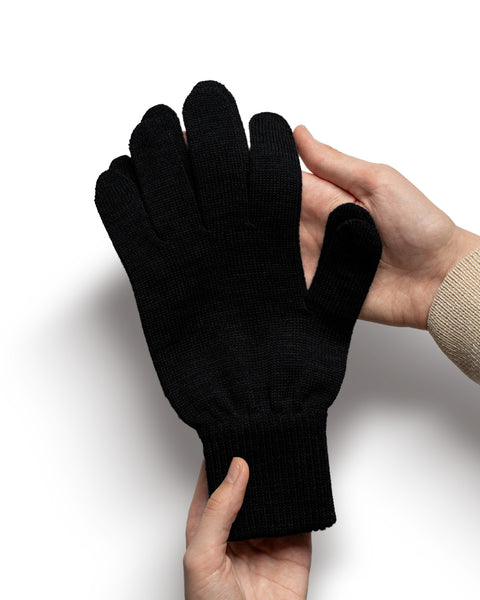 Black Merino wool knit glove held in hands to show texture, thickness, and stretchy cuff.