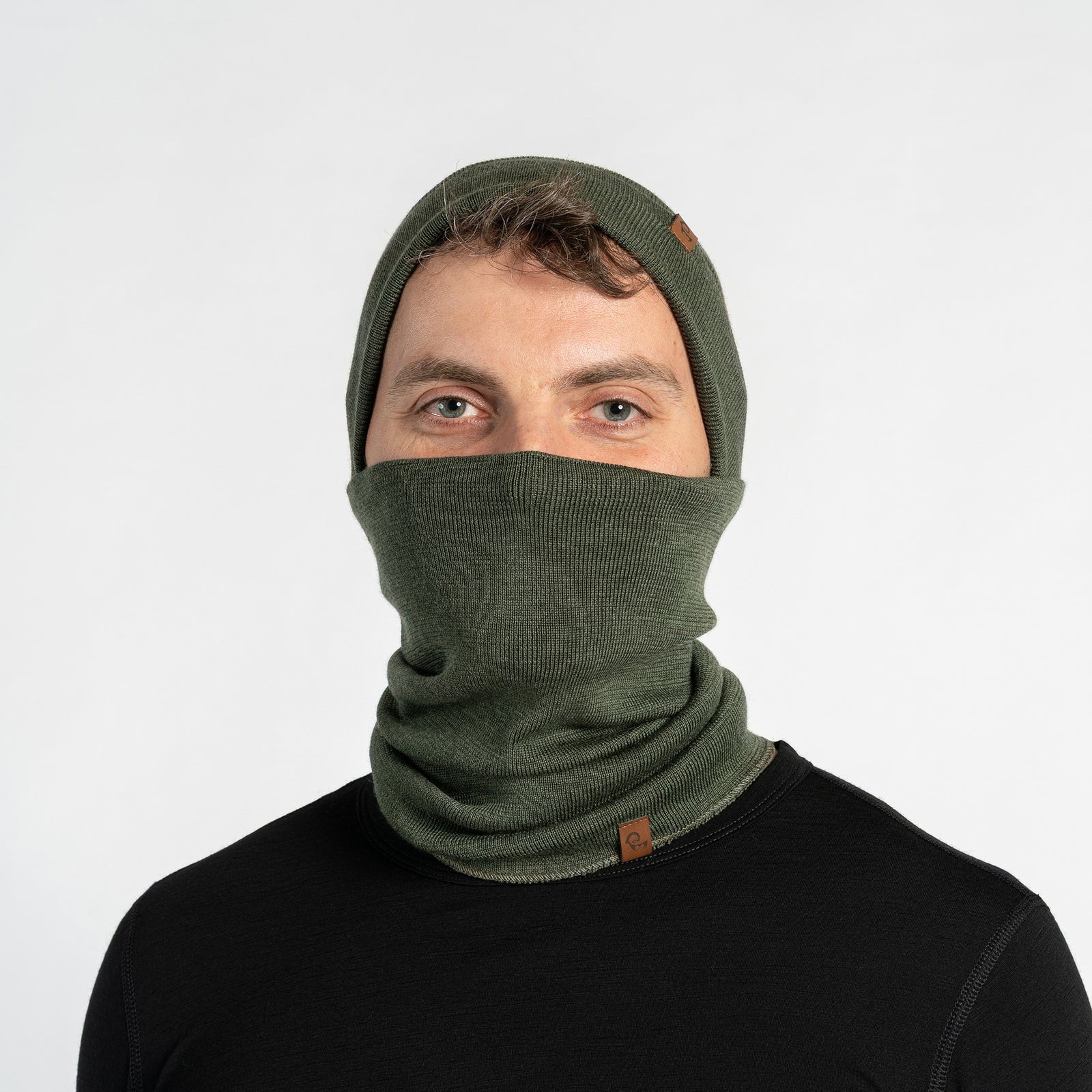 Person wearing a dark gray knit beanie and scarf set on a light gray background