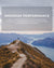 Person standing on a mountain top with a scenic view, promoting merino wool's benefits.