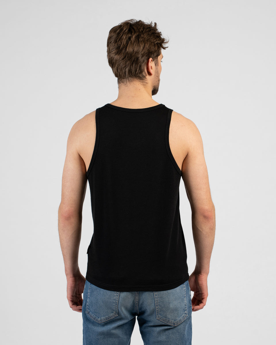 A studio shot showing the back of a man wearing a solid black tank top and medium-wash blue jeans. The background is a plain light grey.