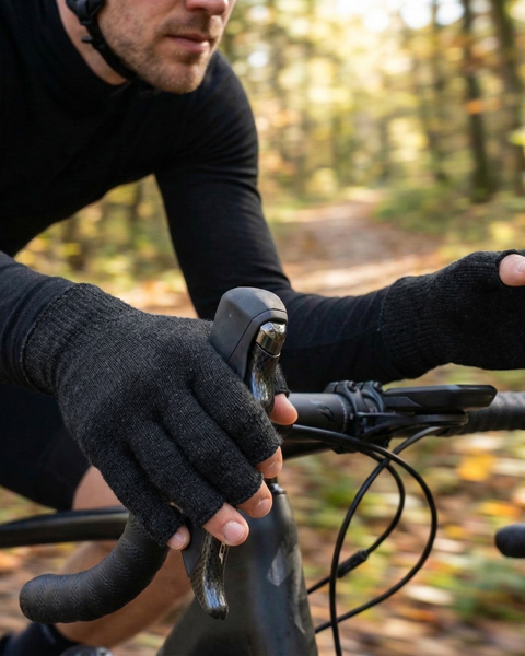 Man cycling in forest wearing dark gray merino wool fingerless cycling gloves, breathable lightweight gloves for spring biking and temperature regulation