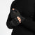 A person wearing a black long-sleeved shirt is shown from the chest up, putting on dark green fingerless gloves. The background is white.