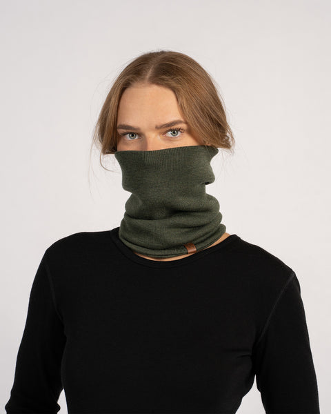 Unisex Merino Neck Gaiter in Dark Green, worn pulled up to cover the lower face, styled with a black top.