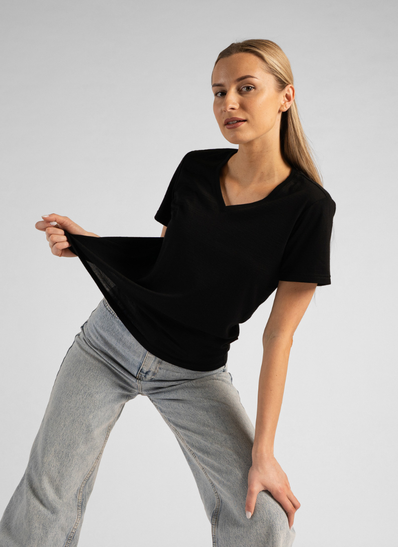 Woman wearing a black oversized t-shirt and gray pants on a plain background