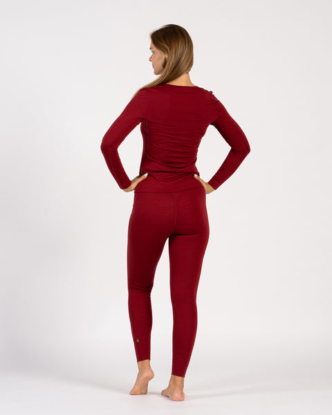 Woman wearing matching royal cherry Merino wool thermal long sleeve top and leggings, back view.