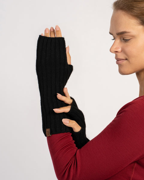 Side-profile of the model showing one raised hand in the long black ribbed wrist glove, fingers partially visible.