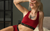 A woman lying on a bed, wearing merino wool sports bra in royal cherry color.