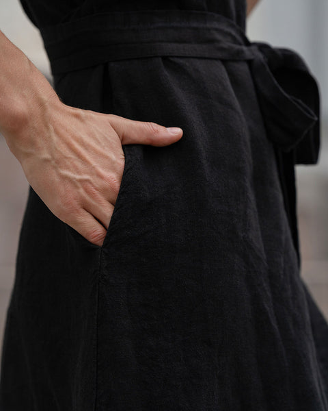 Close-up of a woman putting her hand in a pure black linen dress pocket.