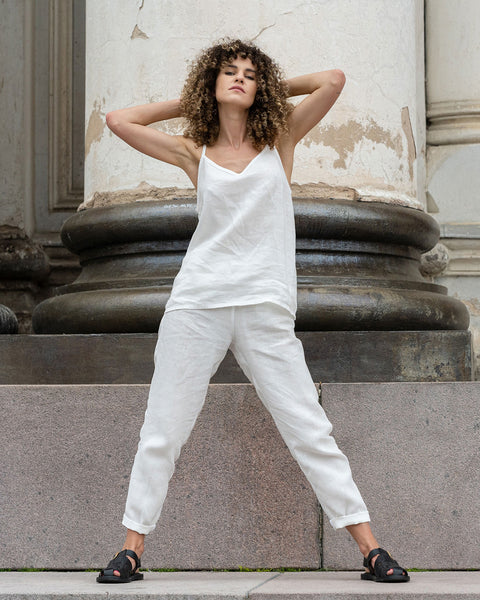 Beautiful woman posing in the city, wearing pure white linen slip top and pure white linen pants with black sandals.