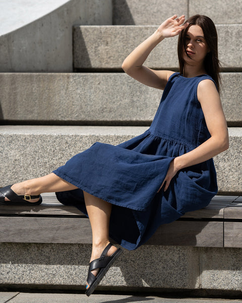 Young woman posing in a city, wearing linen smock dress Maya in a Storm blue cover.