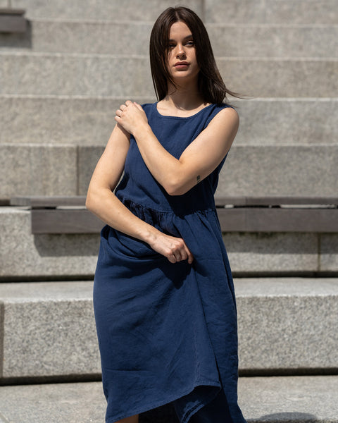 Young woman posing in a city, wearing linen smock dress Maya in a Storm blue cover.