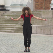 Beautiful woman with curly hair posing in the city wearing pure black linen jumpsuit Nicci, royal cherry merino wool top.